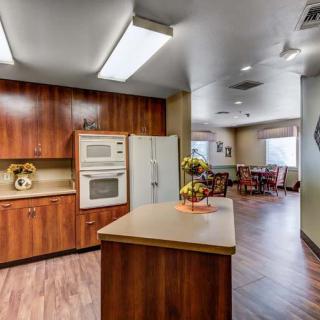 A modern kitchen with wooden cabinetry, featuring an island counter and connected dining area.