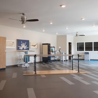 A spacious room designed for physical therapy or rehabilitation, featuring equipment and art.