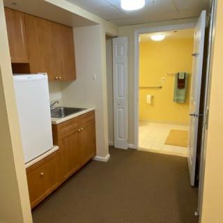 A compact kitchenette leading to a bathroom in a small apartment.