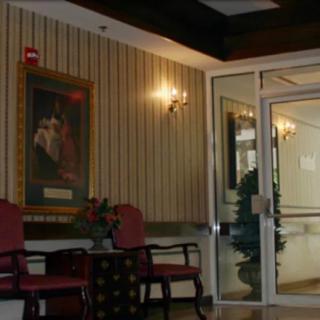 A cozy lobby area featuring chairs, a painting, and glass doors leading to another room.