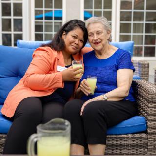 Two women enjoying drinks together on a cozy patio.
