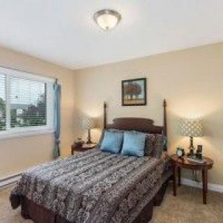 A cozy bedroom with a neatly made bed, two nightstands, and a window providing natural light.