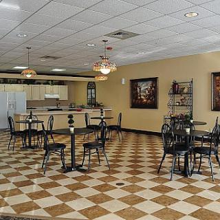 A small cafe interior with checkered flooring and several tables and chairs.