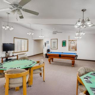 A spacious game room featuring a pool table, card tables, and comfortable seating.