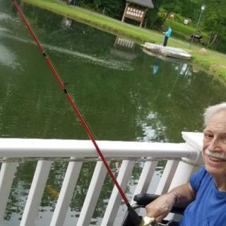 An elderly person enjoying a peaceful day fishing by the lake.