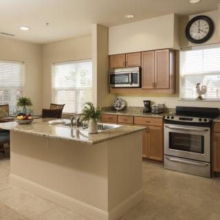 A modern kitchen with an island, stainless steel appliances, and a dining area.