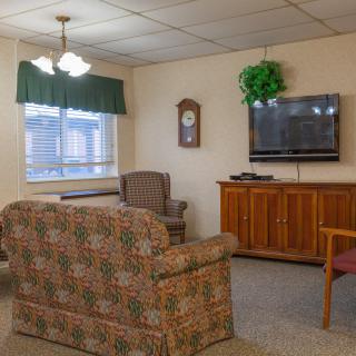 A cozy living room with a sofa, armchair, and a television on a wooden cabinet.