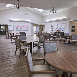 Spacious dining area with multiple tables and chairs under bright lighting.