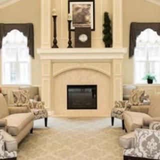 A cozy living room with a central fireplace, surrounded by comfortable seating and elegant decor.