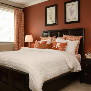 A cozy bedroom with a neatly made bed and warm color scheme.