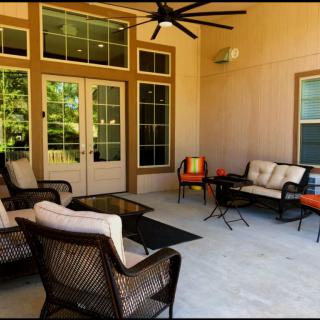 A cozy outdoor patio with comfortable seating and a ceiling fan.