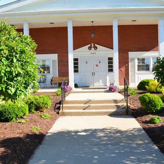 A well-maintained building entrance with white columns and landscaped greenery.