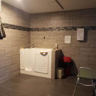 A bathroom designed for accessibility, featuring a walk-in bathtub and tiled walls.