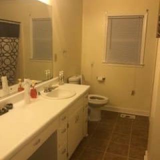 A clean bathroom with a large mirror above the sink and a window next to the toilet.