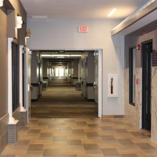 A well-lit indoor hallway with doors on both sides and a tiled floor.