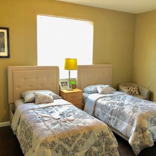A cozy bedroom featuring two twin beds with a shared nightstand and lamp.