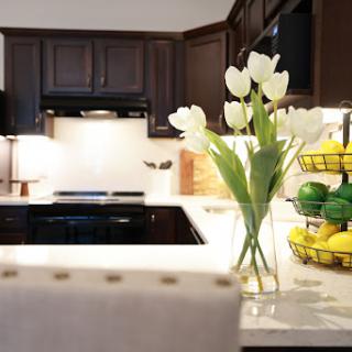 A modern kitchen featuring a stylish arrangement of white tulips and a colorful fruit basket.