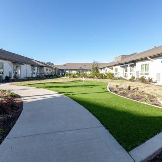 A well-maintained residential courtyard with a central grassy area surrounded by pathways and houses.