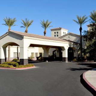A hotel entrance surrounded by palm trees and clear skies.
