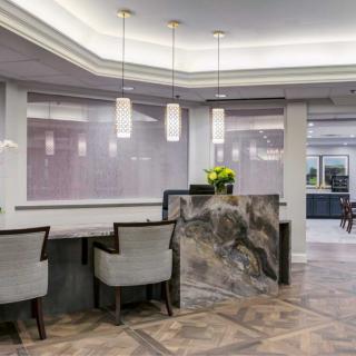 A modern reception area with a marble desk, pendant lights, and seating.