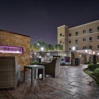 A nighttime view of a hotel patio area with outdoor seating and ambient lighting.