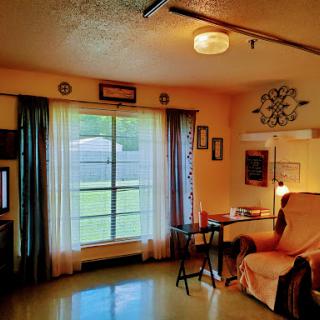 A cozy living room featuring a large window, soft curtains, and comfortable furnishings.
