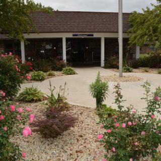 A building entrance surrounded by a well-maintained garden with flowers and shrubs.