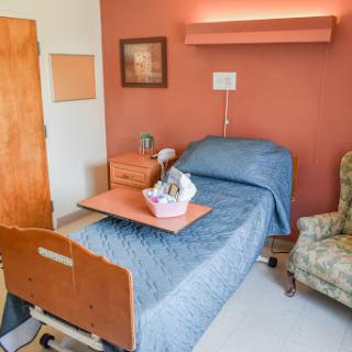 A cozy hospital patient room featuring a bed, a chair, and bedside amenities.
