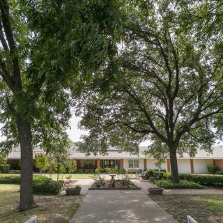 A residential house surrounded by trees and a well-maintained yard.