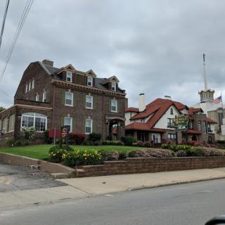 A charming blend of architectural styles, featuring a well-kept front yard under a cloudy sky.