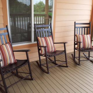 A cozy porch featuring three inviting rocking chairs with striped cushions, perfect for relaxation.