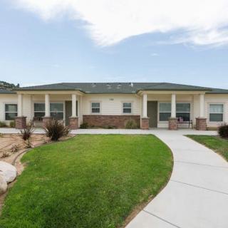 A single-story residential house with a well-maintained lawn and a paved pathway leading to the porch.