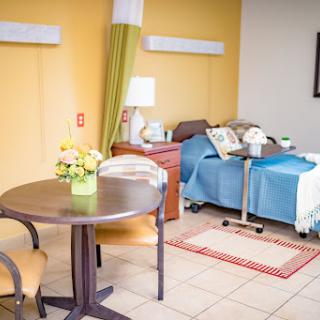 A cozy and welcoming hospital patient room featuring a bed, table, and decorative elements.