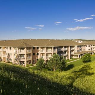 A peaceful apartment complex surrounded by lush greenery under a clear blue sky.