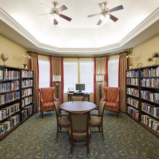 A cozy library reading room with bookshelves, comfortable chairs, and a computer.