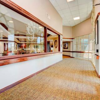 A well-lit office hallway with large windows and carpet flooring.