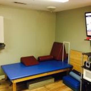 A physical therapy room equipped with an exercise mat and other rehabilitation tools.