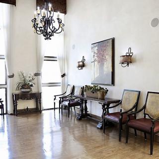 A stylish waiting area with elegant decor, featuring a chandelier and comfortable seating.
