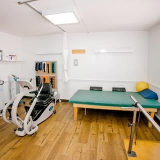 A well-equipped physical therapy rehabilitation room featuring exercise equipment and a treatment table.