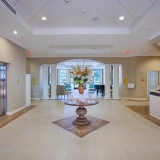 A spacious and elegantly designed lobby featuring a central table with a floral arrangement.
