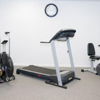 A small gym room with a treadmill, exercise bike, and other fitness equipment.