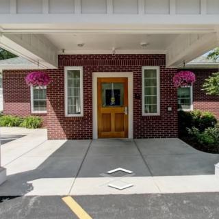 A brick building entrance with a wooden door and hanging flower baskets.