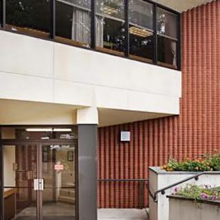 The entrance of a brick building with glass windows and stairs leading up to it.