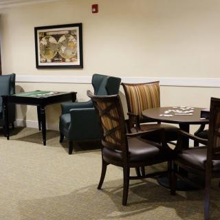 A cozy lounge area with tables, chairs, and wall art.