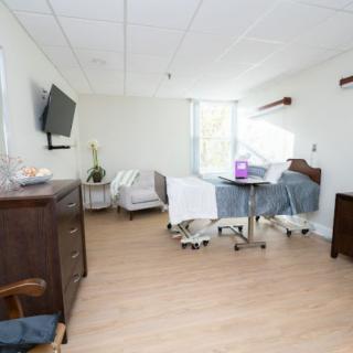 A clean and modern hospital room with a patient bed, television, and medical equipment.