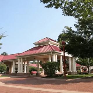 A scenic view of a building with a red roof and white pillars surrounded by trees.