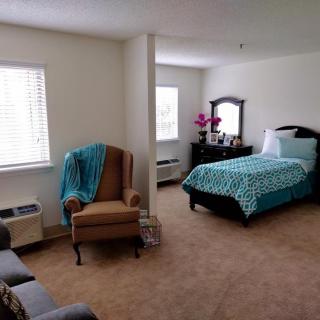 A cozy bedroom with a single bed, armchair, and dresser.