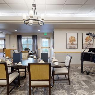 A well-appointed dining room with elegant furniture, a piano, and framed artwork on the walls.