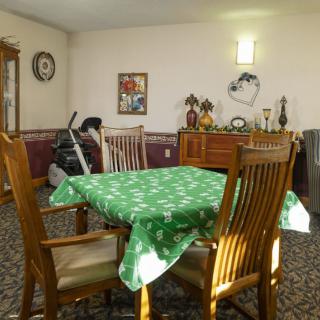 A cozy dining room with a wooden table and chairs, featuring a green tablecloth.