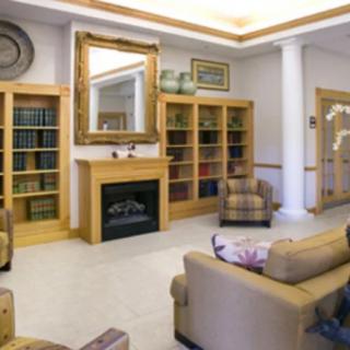 A cozy library interior with bookshelves, a fireplace, and comfortable seating.